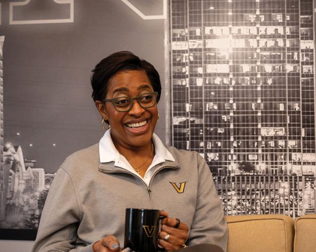 Candice Storey Lee sitting on a gold couch holding a coffee mug