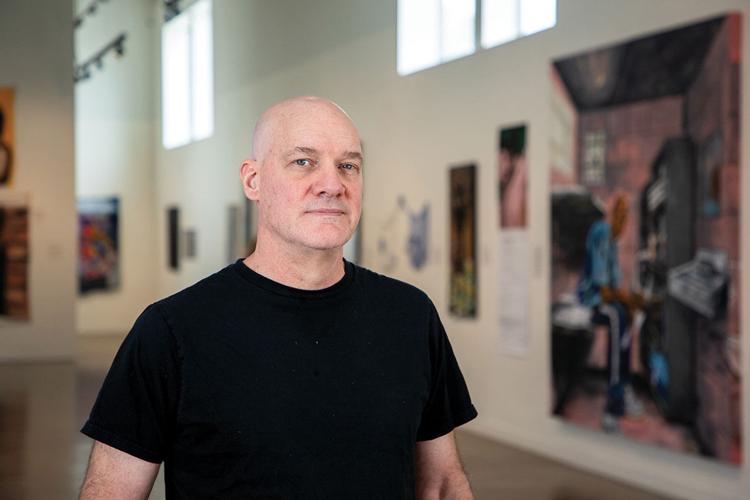 Lain York in a black T-shirt in front of artwork displayed at RADAR615
