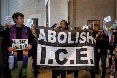 State Rep. Justin Jones holds a banner reading "Abolish I.C.E." and a fellow protestor holds a sign that reads "We Stand Together" at the State Capitol