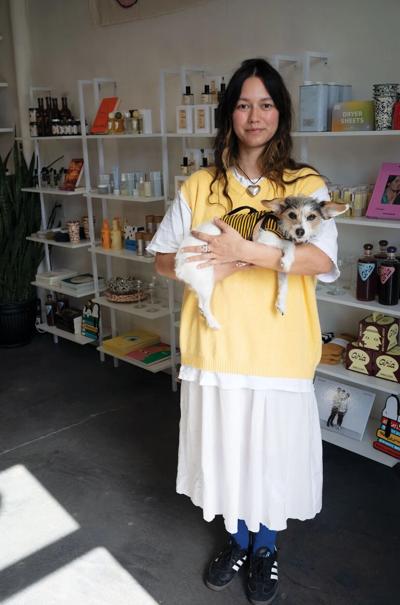 Rebecca Moon holds a small dog in her shop The Green Ray