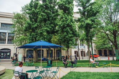 People sit at tables and under an umbrella in a park in downtown Nashville