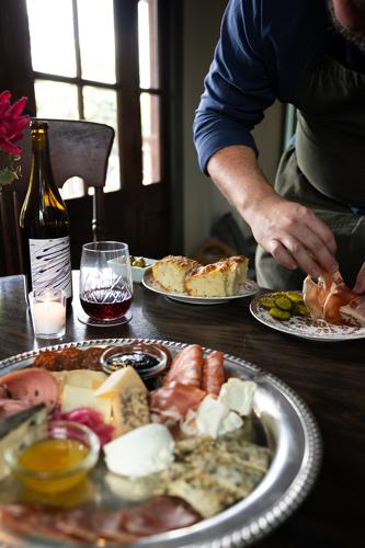 Color photo of plating at Antoinette’s Wines + Provisions in Sylvan Park, featuring charcuterie plated on a silver platter and a glass of red wine.