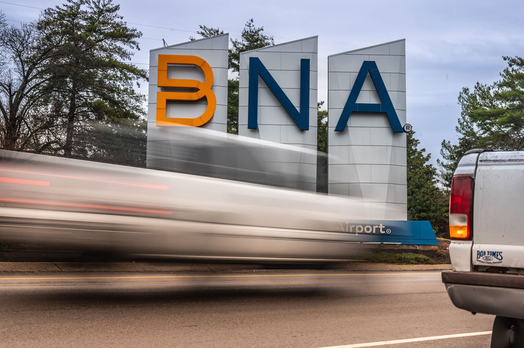 Highway traffic blurs past the BNA sign outside the Nashville Airport