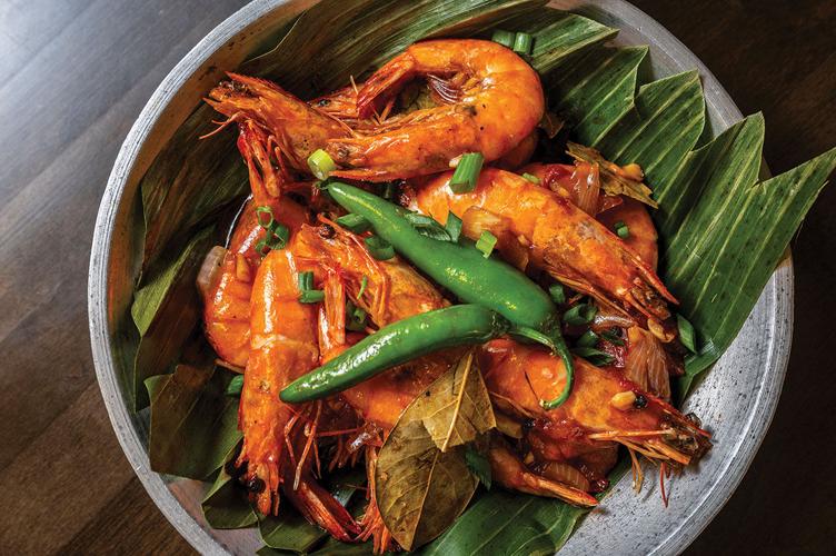 A bowl of shrimp with whole peppers on top