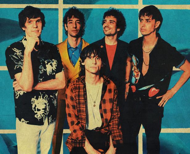 Color press photo of rock band The Strokes, posing in front of a wall composed of large blue tiles