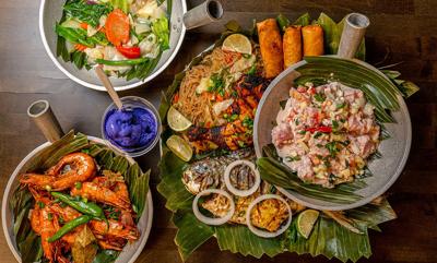 An arrangement of plates, including shrimp, a whole fish, ceviche and a salad