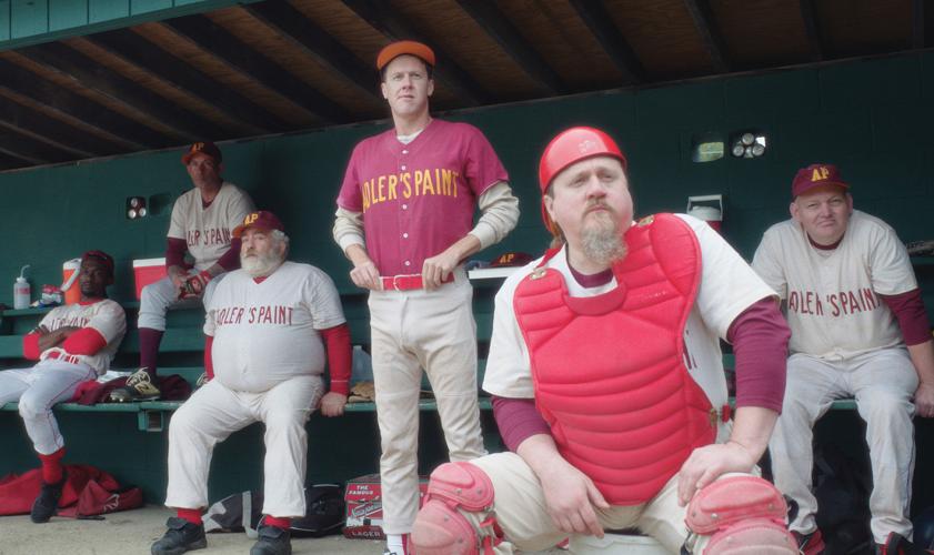 A team of middle-aged baseball players sits in a dugout, from the film Eephus