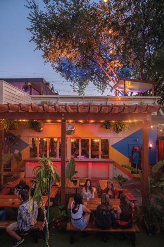 People sit at picnic benches on a colorful patio