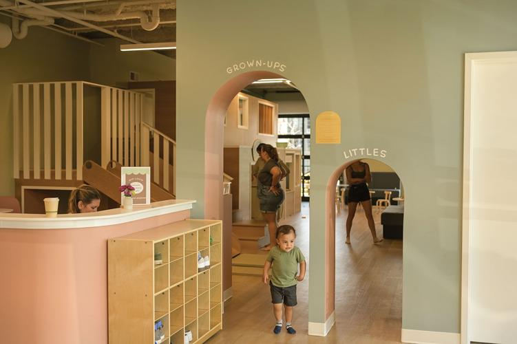 A child at Woodland Play Cafe runs by two arched doorways, the taller one marked "grown-ups" and the shorter marked "littles"