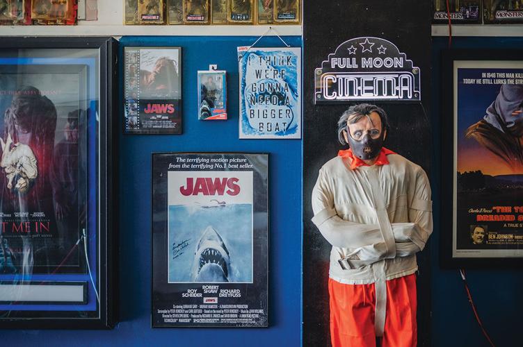 A Hannibal Lector manequin poses next to movie posters of films like Jaws
