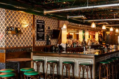 Interior of a bar with green stools and checkered wallpaper