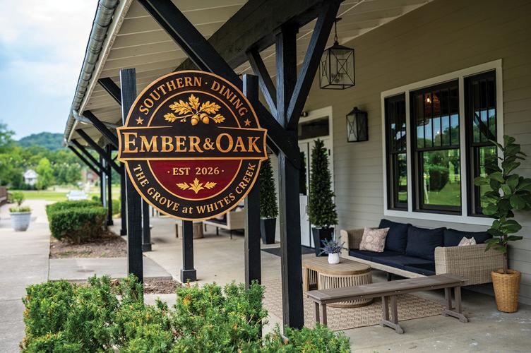 The outdoor exterior of a restaurant, with a small patio seating dislay. A sign reads “Southern Dining - Ember & Oak: est 2026, The Grove at Whites Creek”