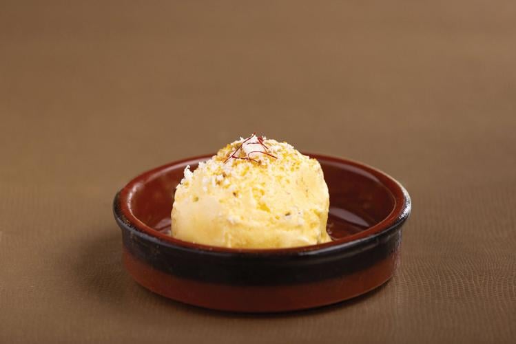 A butter-yellow scoop of ice cream in a red ceramic ramekin.