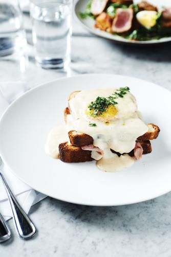 Egg and sauce on top of two pieces of toast with a slice of meat in between