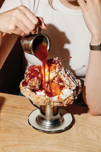 Hot fudge poured over a sundae in a waffle bowl at Black Tap