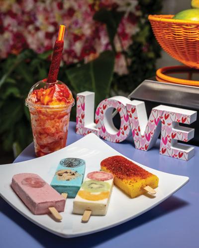 Four popcicles with visible fruit next to a colorful drink and a statue that reads "Love"