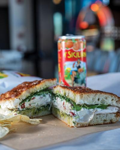 a turkey sandwich cut in half in front of a can of soda