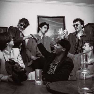 Black and white photo of soul-funk band The Mood Swings, seated around a table and laughing