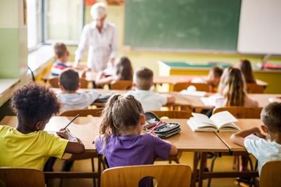 Rear view of elementary students attending a class in the classroom.