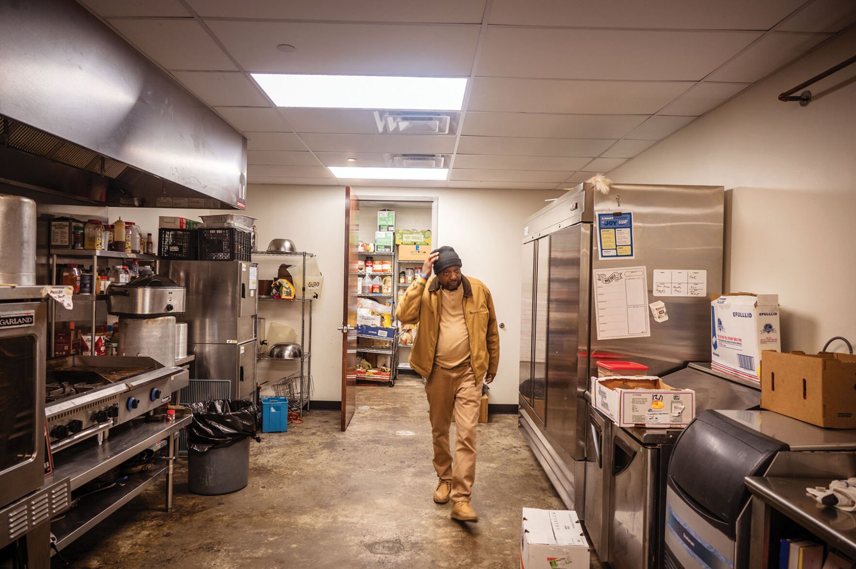 A man in a khaki-colored outfit walks through a kitchen