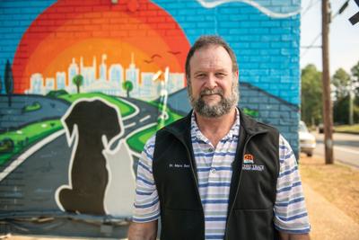 Veterinarian Marc Smith stands in front a mural of a cat and dog watching the sun set over Nashville's skyline