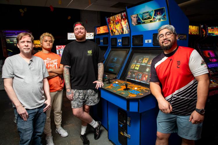 Four community organizers at Game Galaxy stand around arcade cabinets, chief among them Street Fighter: The Movie
