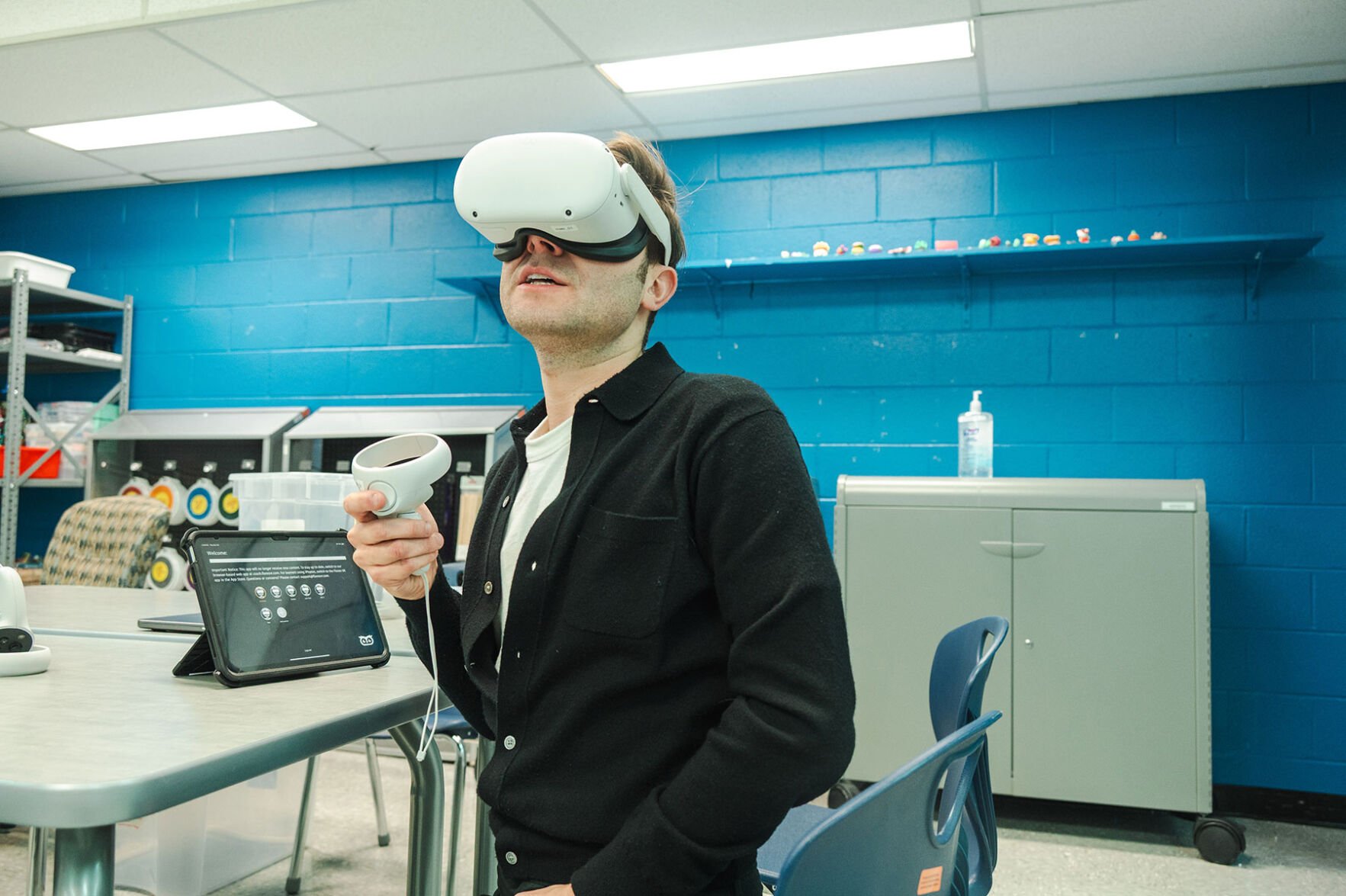 A man dons white goggles and holds a controller to demonstrate virtual therapy