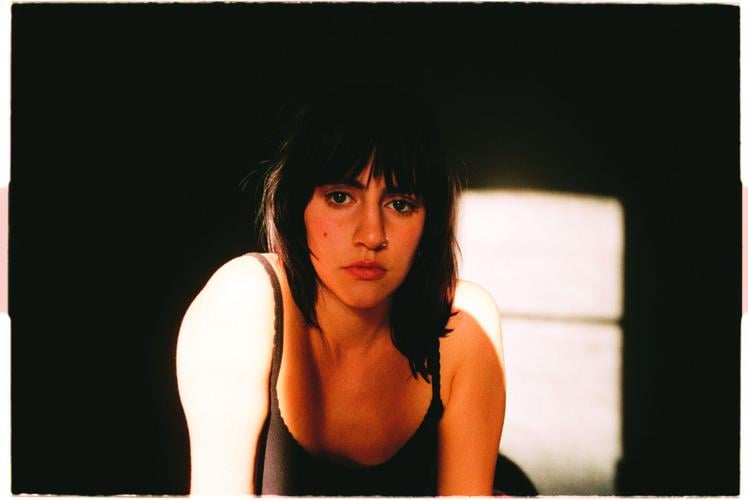 Wilby press photo artist lit from audience left in a dark room looks into the camera