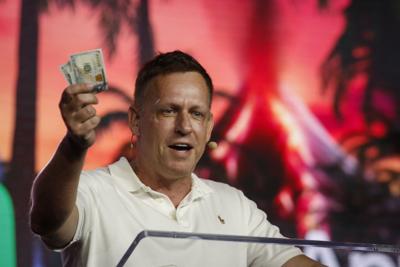 Peter Thiel holds hundred dollar bills as he speaks during the Bitcoin 2022 Conference in Miami, April 2022