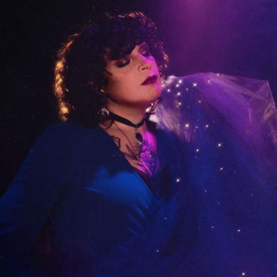 A woman closes her eyes and stands in an ephemeral purple-lighted space