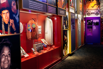 A collection of items including a bomber jacket and a boombox in an exhibit about the evolution and spread of hip-hop in the 1980s. Photographed ahead of the opening of the National Museum of African American Music in 2021.