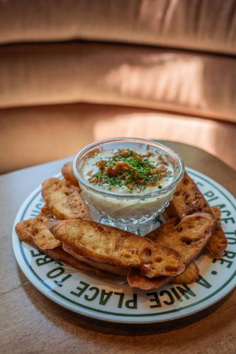 A bowl of cheese dip with pieces of bread surrounding it on a plate that has the message “A nice place to be” circling the rim