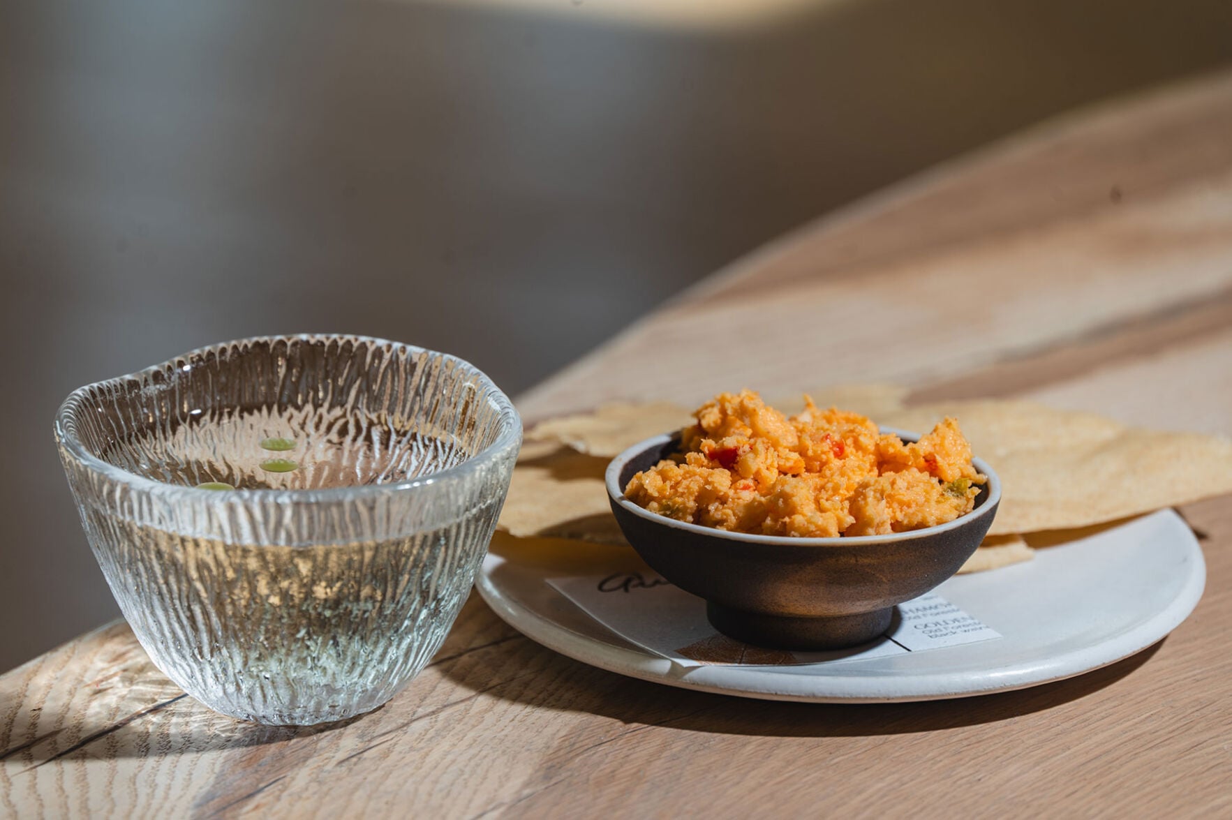 A small glass placed next to a small in of pimento cheese