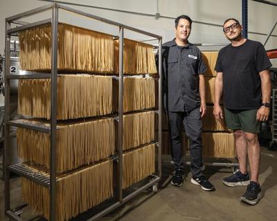 The two Nicoletto brothers stand next to columns of pasta in a kitchen