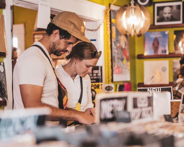 A man and woman browse through rows of vinyl in a record shop