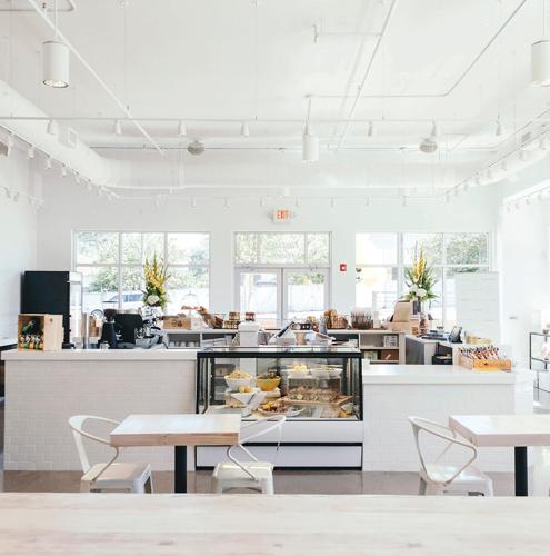 A white counter area in a restaurant with a glass display case featuring bread and fruit
