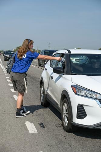 Protester hands a pamphlet to the driver of a car