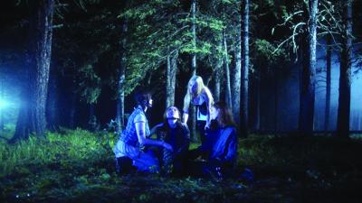 A still from CAMP showing four girls in the woods with eerie blue lights off to the left and right of them