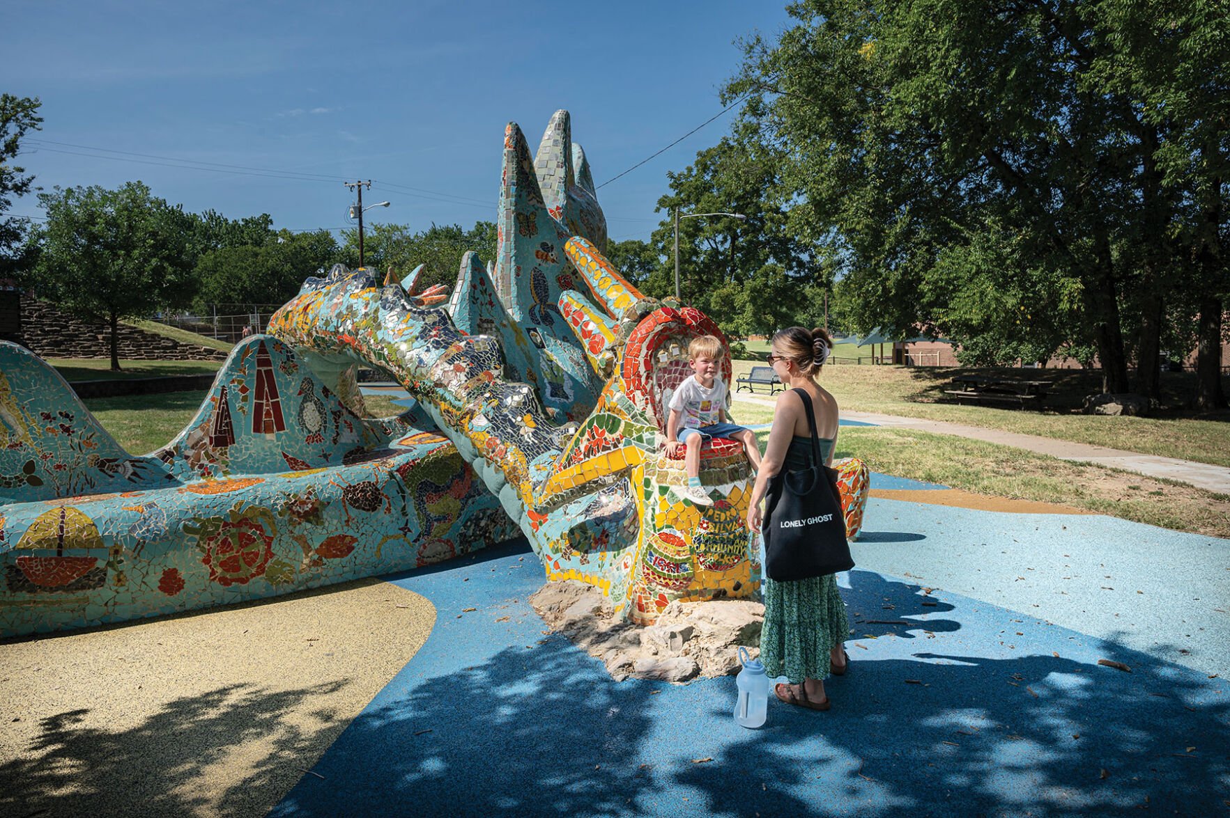 A mother and child play on the colorful dragon statue at Fannie Mae Dees