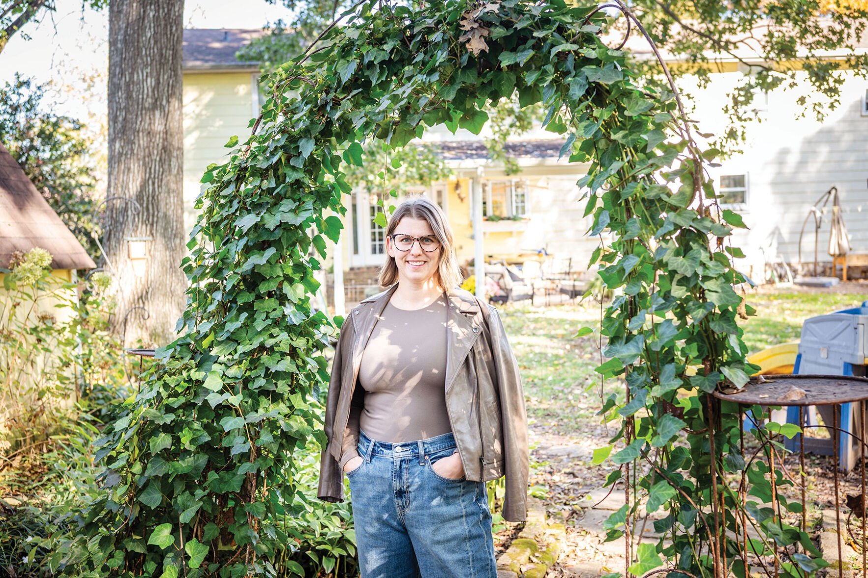 Advocate Kate Cortelyou stands in a verdant backyard