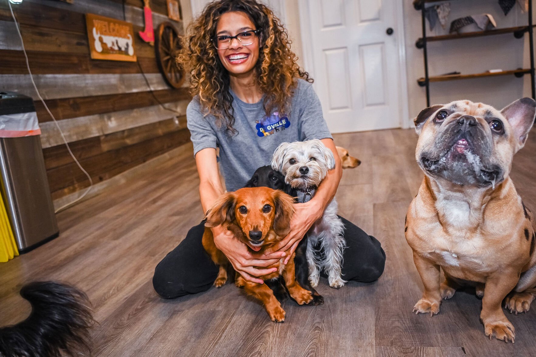 A Dogville staffer poses with three short dogs