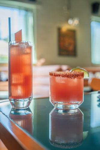 two pink cocktails, one in a tall glass and one in a short.
