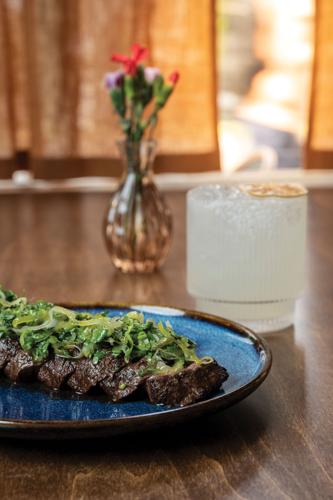 A sliced steak from Tantísimo topped with onion and green herbs