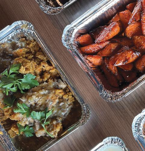 A roasting tray of cornbread stuffing placed next to a roasting tray of glazed carrots