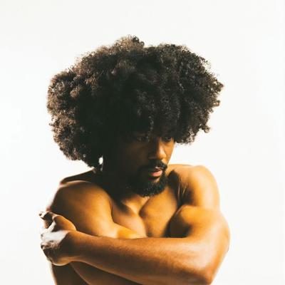 K.O.N artist photo artist poses hugging self as if cold against a white background