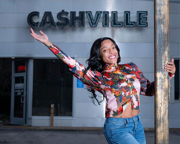 Averianna the Personality poses by the large sign reading '“Ca$hville” outside Cashville Gold and Silver Buyers on Eighth Avenue South