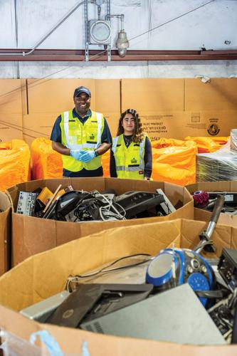 East Convenience Center employees Darius Coleman and Ashley Garcia photographed amid an array of electronics being sorted for recycling