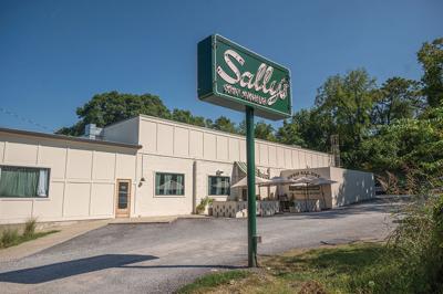 A sign reading “Sally’s” in front of a boxy white building
