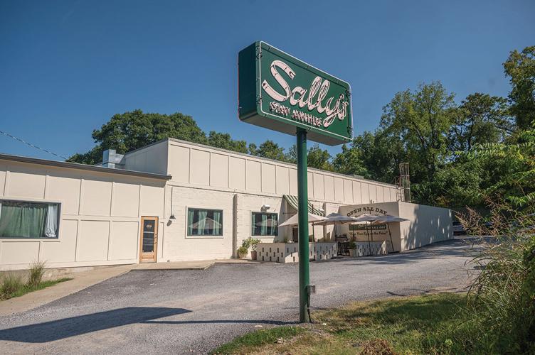 A sign reading “Sally’s” in front of a boxy white building
