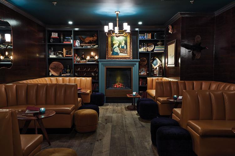 A fireplace and several leather booths in a dim, upscale library-themed dining space